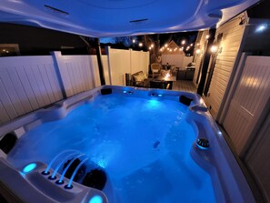 A large McKinely model Arctic Spa with Motorized Covana cover just off the Colonial's primary family room with outdoor seating, fire pit and BBQ