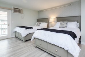 Two queen beds come freshly made with sheets, duvet, throw blanket and storage.