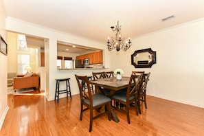 Dining area open to kitchen and living area. Bar sitting at kitchen counter.