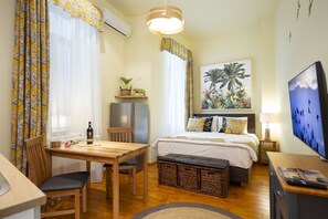 Expansive area with a jungle-themed decor, including a fully equipped kitchen, dining table, comfy bed, and TV