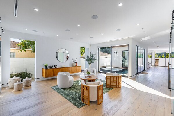 Throughout the first floor, floor-to-ceiling sliding windows drench the home in natural light, and seamlessly blend the home’s indoor and outdoor areas. Custom window shades throughout offer privacy.