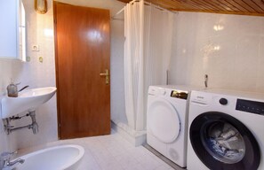 The bathroom with washing machine and dryer