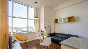 A spacious living room with abundant natural light, featuring comfortable seating arrangements and a large window offering a view of the outdoors #city #airbnb