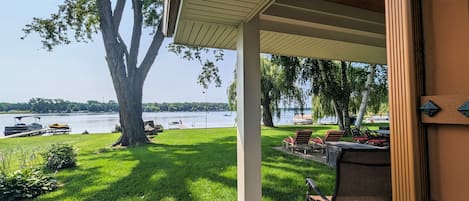 Covered patio outside of the primary bedroom overlooking the lake and yard