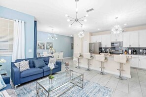 Bright communal space thoughtfully divided into a living room, dining area, and kitchen for a harmonious atmosphere.