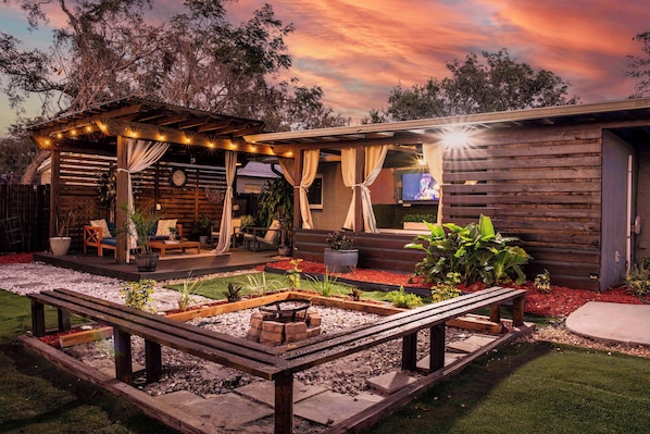 Outdoor living space. Equipped with outdoor smart TV, outdoor dining table & chairs, lounge area, firepit, outdoor grill & more
