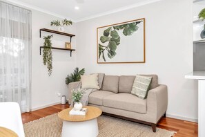 Relax in the cosy living area, featuring a comfortable sofa and tasteful greenery that adds a touch of natural beauty to the space.