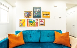 Vibrant eclectic-bohemian living room featuring a cozy seating area, colorful decor, and a 65-inch TV with a soundbar for premium entertainment
