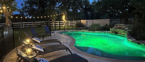 Enclosed pool and spa with waterfall at sunset