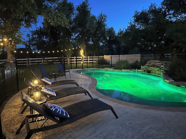 Enclosed pool and spa with waterfall at sunset