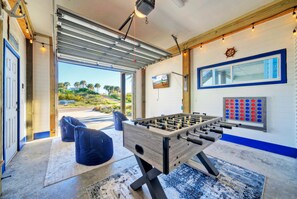 Garage game room with foosball, a TV, games, and comfortable seating.