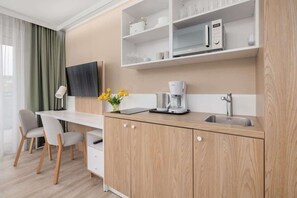 A compact kitchenette with wooden cabinets, open shelves, and a small dining area.

