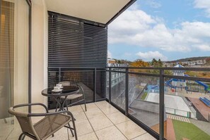 A balcony with outdoor seating, glass railing, and a scenic view.

