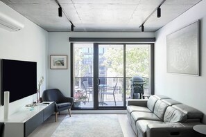 Relax in style in the sunlit living space, featuring a comfortable leather lounge and a large TV.