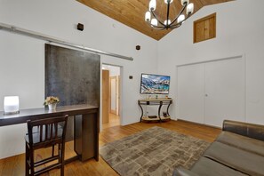 The comfortable living area includes a sofa, flat-screen TV, and a table suitable for dining or working.