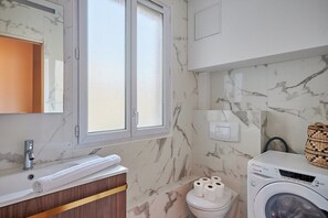 Salle de bain avec toilette et machine à laver