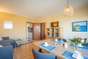 Das große Wohnzimmer mit Essbereich und TV in der Ferienwohnung Inselblume 11