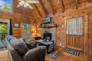 Living room with fireplace, tv, and deck access at Cloud 9, a 1-bedroom cabin rental located in Pigeon Forge