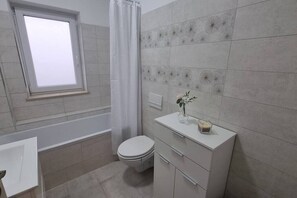 Bathroom with bathtub, toilet, fluffy towels and free toiletries