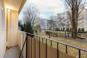 A balcony with a view of a green courtyard surrounded by residential buildings.

