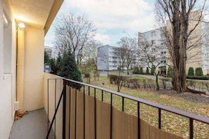 A balcony with a view of a green courtyard surrounded by residential buildings.