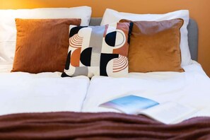 A close-up of the bed with decorative pillows in earthy tones and geometric patterns.