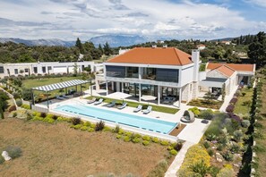 Spacious sunny terrace with jacuzzi and heated pool surrounded by sun loungers in fron tof the entrance to the Brac holiday home rental