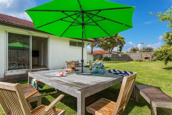 The fully fenced backyard offers ample seating for the group to enjoy meals alfresco, with an umbrella to provide some shade in the summer sun.