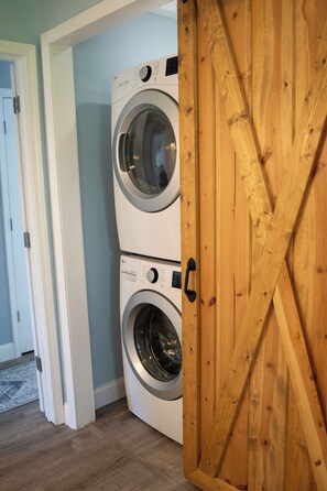 Slide the barn door open to reveal full size modern laundry room, ironing board.
