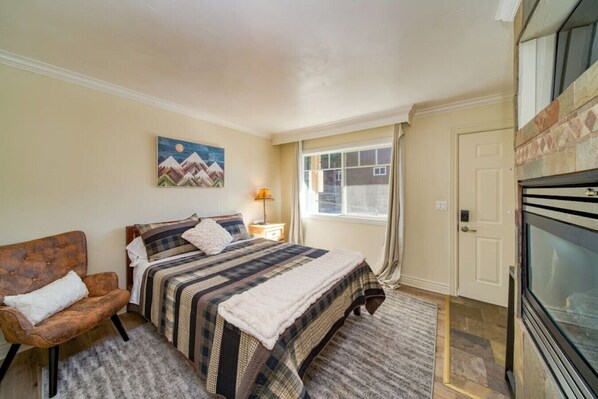 Main living space with a queen bed, sitting chair, gas fireplace, and smart TV with Netflix.