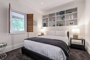 The spacious first bedroom includes a queen-size bed with side tables and reading lamps, while both bedrooms include a panel wall heater.
