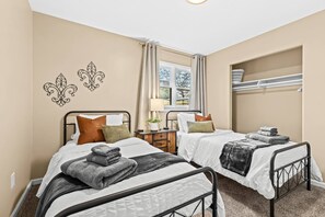 Charming twin bedroom with artistic wall accents and warm, earthy tones, perfect for restful nights and refreshing mornings