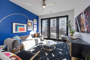 Bright open living space featuring a smart flat-screen TV, designer furnishings throughout, and access to a private patio.