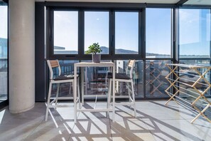 This charming enclosed balcony features two inviting chairs and expansive windows, creating a sunny and serene retreat perfect for unwinding.