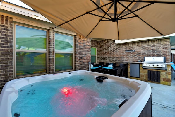 Hot tub under the umbrella for a relaxing time . 