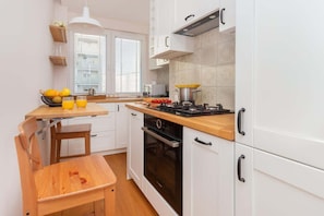 Compact kitchen with modern appliances, including a stove, oven, and cabinets in a light color scheme.