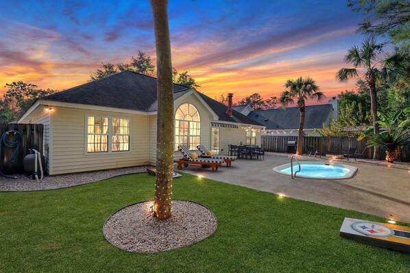 Private backyard with a warm fire pit, plunge pool, grill, and lounge chairs.
