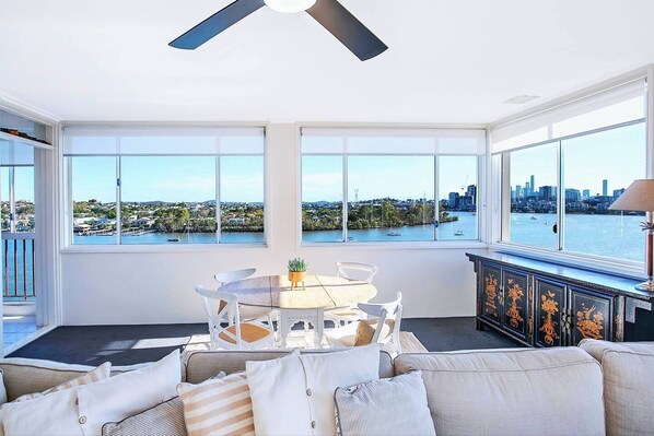 Experience seamless transitions as the living area gracefully connects to the dining space, offering a panoramic view of the tranquil river scenery.