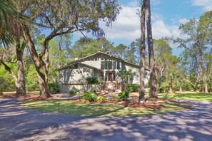 Experience the essence of famous Lowcountry indoor-outdoor living as you step through large sliding doors onto a deck overlooking an expansive private backyard surrounded by serene nature.