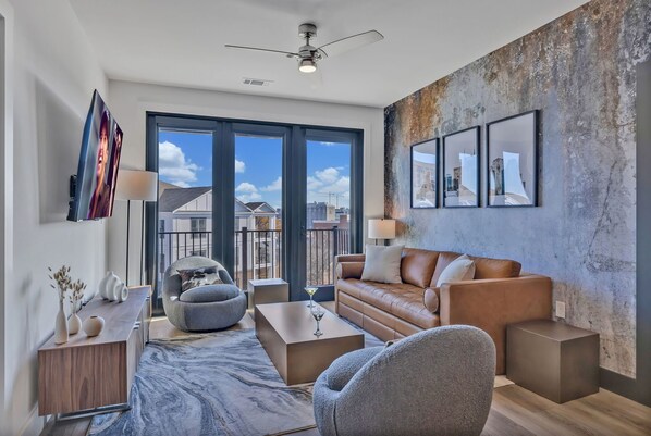 Bright living room with comfortable seating, smart TV, designer decor, and access to the private patio.