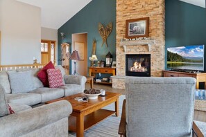 A cozy main-level living room offers an inviting space to sit back and relax while you warm up by the fire.