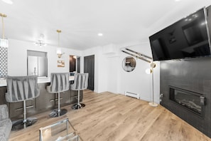 Living area with a mounted TV over a gas fireplace, a queen sleeper sofa, and balcony access.