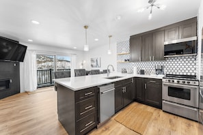 Full kitchen with stainless steel appliances, and breakfast bar.
