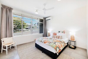 The second unit's primary bedroom is set with a comfortable queen bed under the cooling breeze of a ceiling fan and split-system cooling.