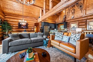 Experience the perfect mountain getaway in this open-concept living and kitchen area. Modern amenities meet classic cabin comfort under the majestic gaze of an antler chandelier. 