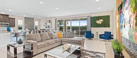 Living area with 86" flat-screen TV, comfy couch, and access to resort-style private pool