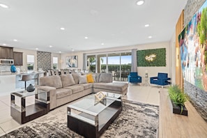 Living area with 86" flat-screen TV, comfy couch, and access to resort-style private pool