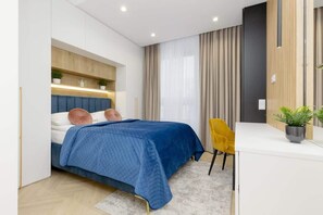 A cozy bedroom with a blue comforter on the bed and a bedside table adorned with a small lamp.