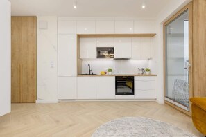 A compact and stylish kitchen with white cabinetry, modern appliances, and a light-colored backsplash.