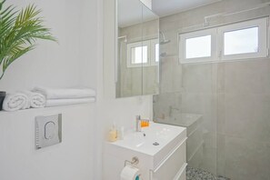 Bathroom with walk in shower, towels, complimentary toiletries.